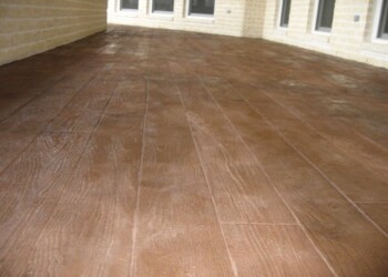 Finished stamped concrete patio with wood grain pattern in a residential backyard. Stamped concrete patio with a wood grain pattern in a residential backyard.