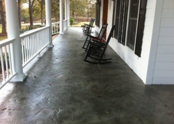 Concrete porch with rocking chairs and white railing at a house in a rural area. Concrete porch with rocking chairs and white railing at a house in a rural area.