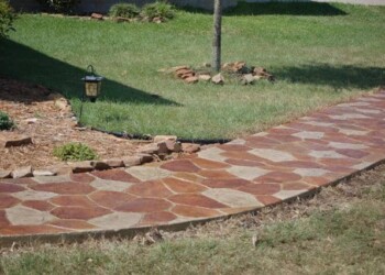 Stamped concrete walkway with a natural stone pattern in a yard. Stamped concrete walkway with a natural stone pattern in a yard.