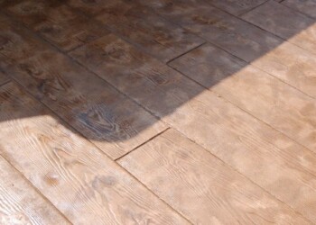 Stamped concrete designed to look like wood planks in a residential patio. Close-up of stamped concrete resembling wood planks in a patio.