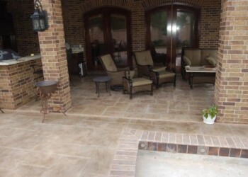 Finished stamped concrete patio with seating area in Eads, Tennessee. Stamped concrete patio with outdoor furniture and brick house in Eads, Tennessee.