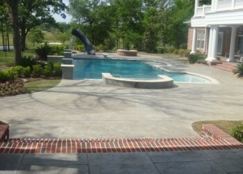 Stamped concrete patio with pool and garden in a residential backyard. Stamped concrete patio with a pool and garden in a residential backyard.
