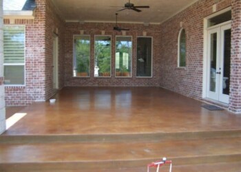 Outdoor patio with acid-stained concrete floor and brick walls, part of a residential home in Euless, Texas. Finished outdoor patio with acid-stained concrete floor and brick walls in a residential home.