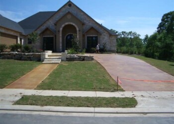 Freshly poured concrete driveway and sidewalk at a residential home in Euless, Texas. New concrete driveway and sidewalk in front of a brick house in Euless, Texas.