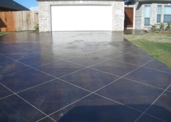 Concrete driveway with acid stain finish in front of a garage. Freshly acid stained concrete driveway in a residential neighborhood.