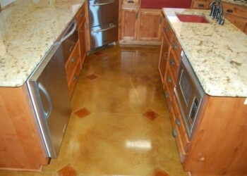 Kitchen with acid-stained concrete floor, wooden cabinets, and granite countertops. Finished acid-stained concrete kitchen floor with wooden cabinets and granite countertops.
