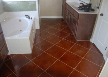 Bathroom with acid-stained brown tile floor, bathtub, and wooden cabinets. Bathroom with acid-stained brown tile floor, bathtub, and wooden cabinets.