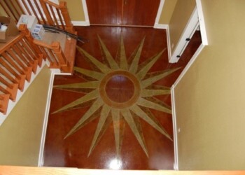 Interior acid stained concrete floor with a sunburst design in a residential entryway. Decorative concrete floor with a sunburst pattern in a home interior.