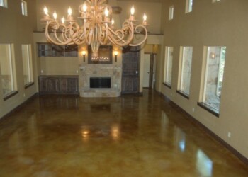 Living room with acid-stained concrete floor, chandelier, and fireplace in ECD Concrete's project in a local home. Interior of a living room with polished acid-stained concrete floor and a large chandelier.