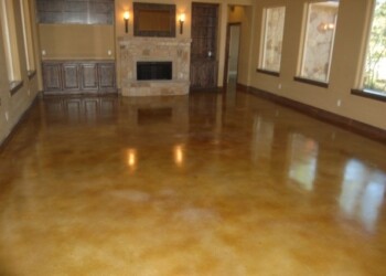 Finished acid-stained concrete floor in a spacious living room in Eads, Tennessee. Interior of a living room with polished acid-stained concrete floor and stone fireplace.