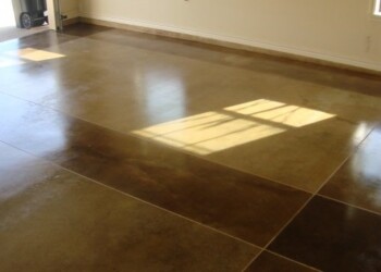Finished acid-stained concrete floor in a residential interior. Interior view of a concrete floor with acid staining in a room with windows and a door.