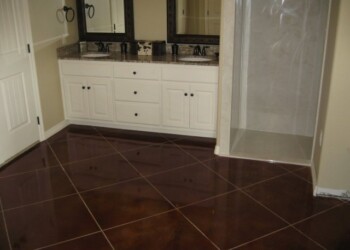 Bathroom with newly stained concrete floor and white vanity in a home. Interior view of a bathroom with a dark stained concrete floor and white vanity with two sinks.