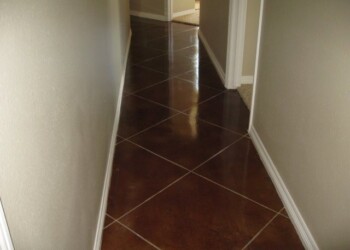 Interior acid stained concrete floor in a residential hallway. Polished brown concrete floor in a hallway with white baseboards.