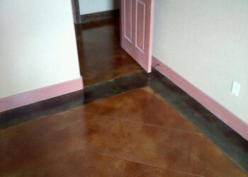 Finished acid-stained concrete floor in a room with pink door and beige walls. Interior room with polished acid-stained concrete floor and pink door.