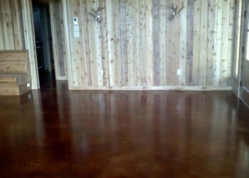 Polished concrete floor with wood-paneled wall in a home interior. Interior room with polished concrete floor and wood-paneled wall in a residential home.