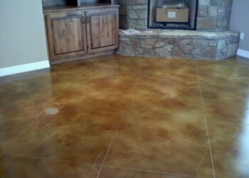 Finished acid stained concrete floor in a living room with stone fireplace. Interior of a room with acid stained concrete floor and stone fireplace.