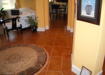 Living room with acid-stained concrete floors and a decorative rug in a home in Eustis, Florida. Interior view of a home with acid-stained concrete floors in a yellow-walled living area.