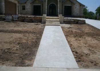 Concrete sidewalk and steps in front of a new house during construction. Concrete sidewalk leading to a house under construction in a residential area.