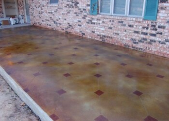 Exterior acid stained concrete patio with decorative tile accents in a residential yard. Finished exterior acid stained concrete patio with decorative tile accents in a residential yard.