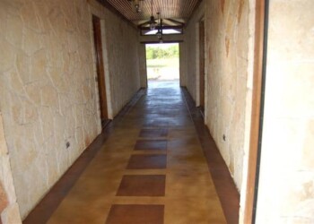 Interior hallway with acid-stained concrete floor and stone walls in a home. Long hallway with acid-stained concrete floor and stone walls at a residential property.
