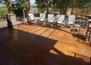 Finished concrete patio with acid stain and outdoor chairs in a backyard. Concrete patio with acid stain finish and outdoor seating in a backyard.