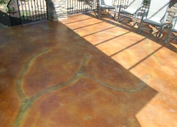 Concrete patio with acid stain finish and outdoor furniture in a sunny setting. Concrete patio with acid stain finish and shadowed chairs along the edge.