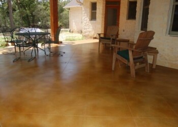 Concrete patio with acid stain finish and outdoor furniture in a residential yard. Exterior concrete patio with acid stain finish and outdoor furniture in a residential yard.