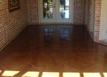 Finished acid stained concrete floor inside a home, with brick walls and glass doors. Interior view of a newly acid stained concrete floor in a residential space.