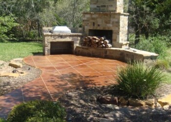 Outdoor concrete patio with acid stain, brick fireplace, and garden in the background. Finished outdoor concrete patio with acid stain, brick fireplace, and garden in the background.