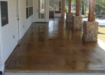 Exterior concrete patio with acid stain, stone pillars, and wooden posts in a residential yard. Finished exterior concrete patio with acid stain, stone pillars, and wooden posts in a residential setting.