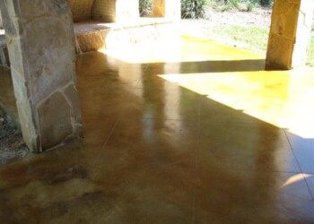 Exterior acid stained concrete floor in a residential setting, showing a glossy finish and natural stone porch. Finished exterior acid stained concrete floor with a glossy finish under a stone porch.