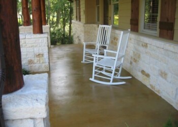 Concrete porch with acid stain finish and two white rocking chairs in front of a house. Concrete porch with acid stain finish and white rocking chairs in front of a house.