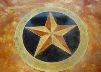Custom engraved concrete star emblem on a textured surface. Concrete star emblem with a black background and gold outline on a textured surface.