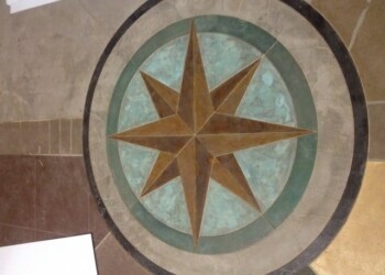 Custom engraved compass rose on concrete floor in a building. Decorative compass rose design on concrete floor with blue and brown tones.