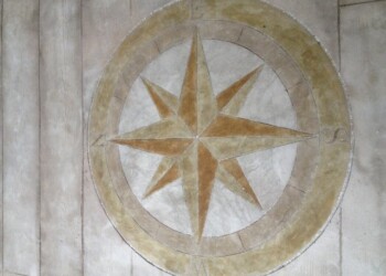 Decorative compass rose on a concrete wall, part of a custom engraving project. Decorative compass rose with gold and beige tones on a concrete wall.