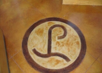Concrete floor with custom engraved circular logo for ECD Concrete in San Antonio. Custom circular concrete engraving with a stylized 'L' and 'P' inside.