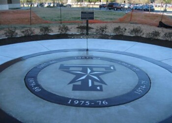 Concrete emblem with military insignia and dates, installed outdoors at a construction site. Concrete circular emblem with military insignia and dates, outdoors at a construction site.