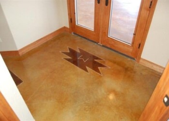 Custom engraved concrete floor with starburst pattern at the entrance of a home. Decorative concrete floor with a starburst design near the door in a residential entryway.