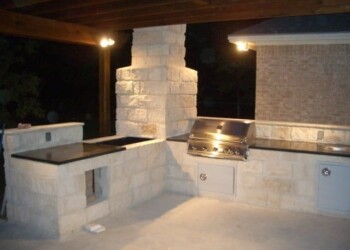 Stone countertops and built-in grill in an outdoor kitchen in Eads, Tennessee. Outdoor kitchen with stone countertops and built-in grill at night.