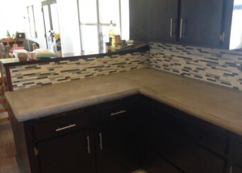 Concrete countertop installed in a kitchen with a mosaic tile backsplash. Concrete kitchen countertop with a mosaic tile backsplash in a modern kitchen.