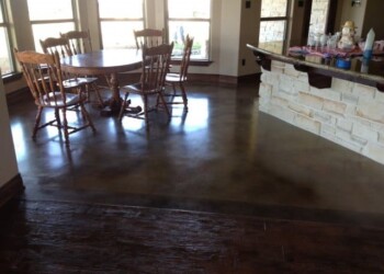 Polished concrete floor in a dining area with wooden table and chairs. Polished concrete floor in a dining area with wooden table and chairs in a home.