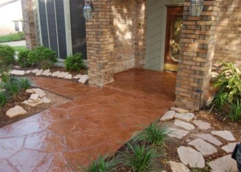 Stamped overlays on concrete porch with brick columns and garden in front of a house. Stamped concrete porch with brick columns and landscaped garden in front of a house.