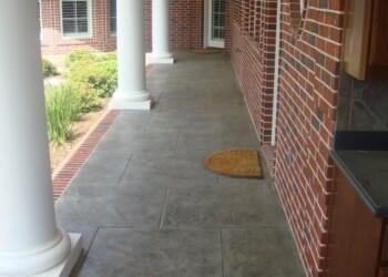 Finished stamped concrete porch with columns at a home in Eads, Tennessee. Stamped concrete porch with white columns and brick house in Eads, Tennessee.