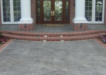 Stamped concrete driveway with brick border in front of a house in Eads, Tennessee. Stamped concrete driveway with brick border in front of a house with brick exterior and white columns.