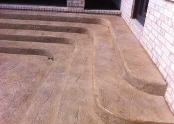 Stamped concrete driveway with curved design near a brick house in Eads, Tennessee. Stamped concrete driveway with curved design near a brick house in Eads, Tennessee.
