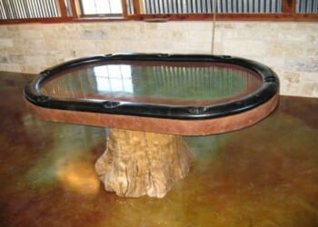 Custom concrete poker table with wood base in ECD Concrete workshop. Concrete poker table with a black rubber edge and a wood base in a workshop.