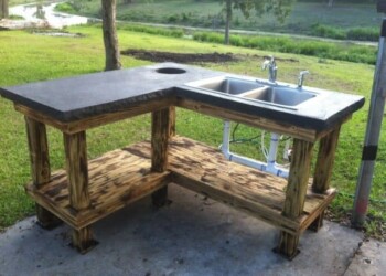 Concrete countertop with sink installed outdoors in a backyard. Outdoor concrete countertop with sink and wooden base in a backyard setting.