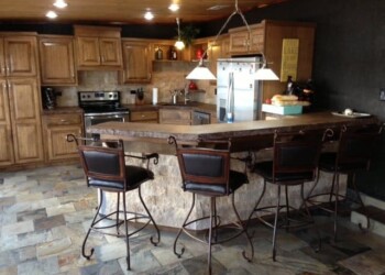 Kitchen with granite countertops, wooden cabinets, and a breakfast bar with four chairs. Kitchen with granite countertops, wooden cabinets, and a breakfast bar with four chairs.