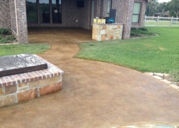 Stamped overlays on concrete patio and walkway at a home in a rural area. Stamped concrete patio with a curved walkway and brick accents at a residential home.