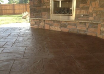 Finished stamped concrete patio with stone fireplace in a backyard. Stamped concrete patio with a stone fireplace in a backyard.